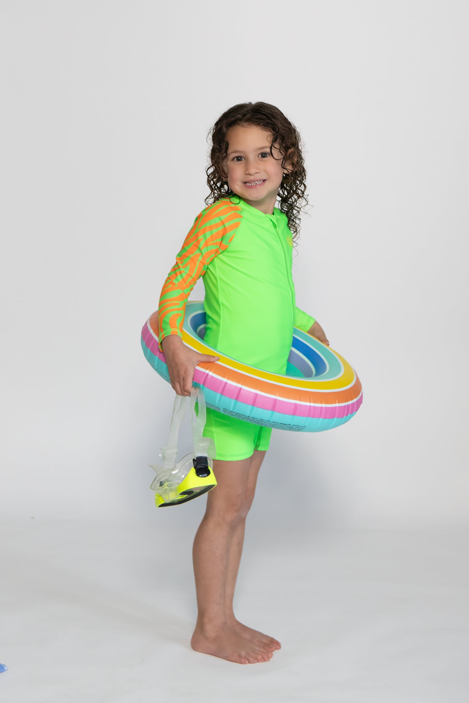 Child wearing bright Green Sea Me Swimwear Zebra Swimsuit
posing in front of White Background.
